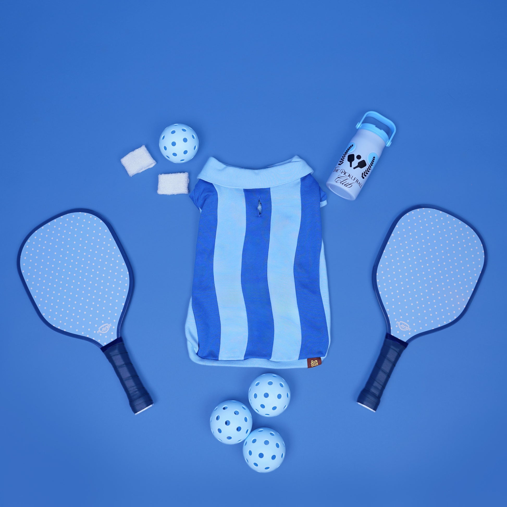 Blue and white sports equipment including paddles, balls, and a bag on a blue background