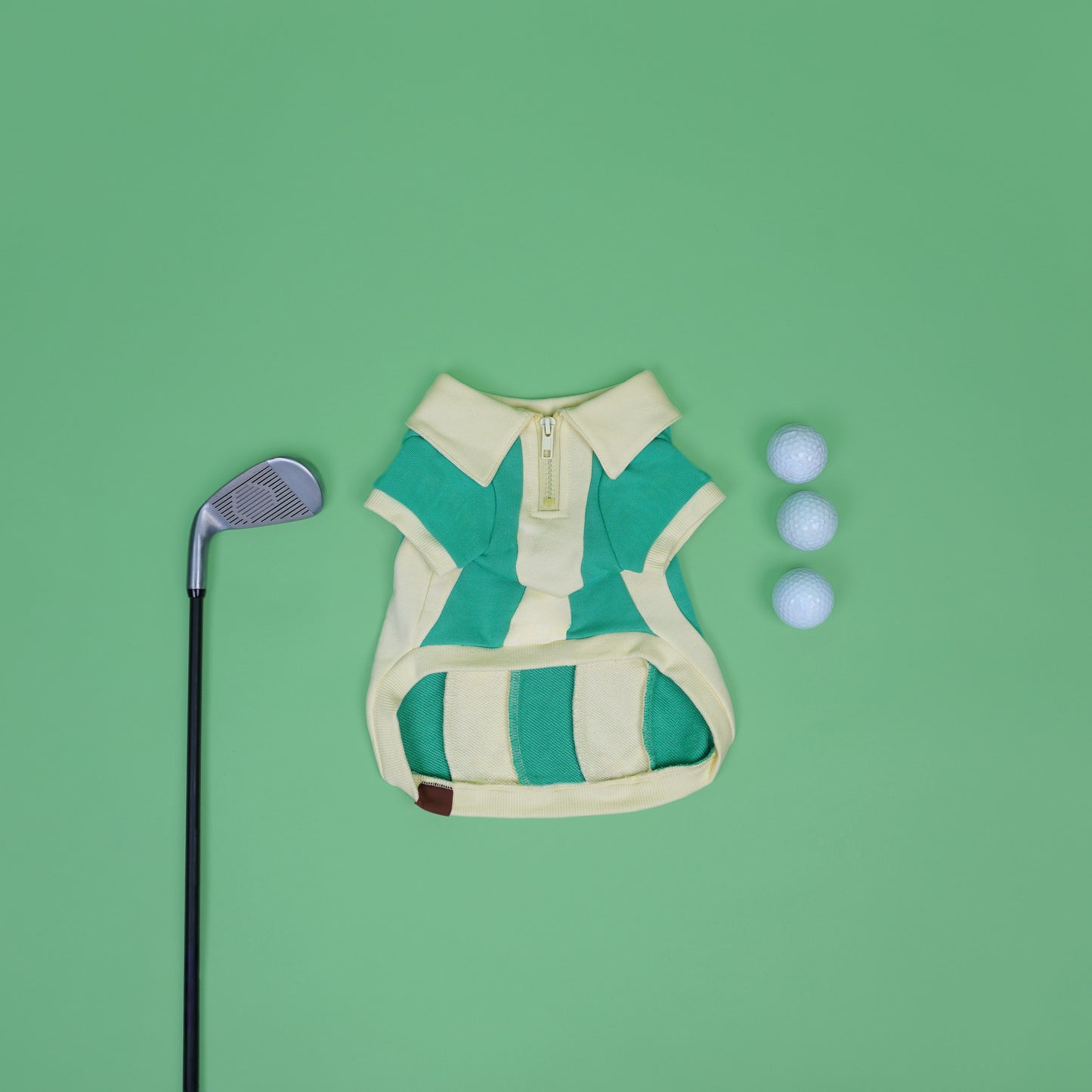 Green and beige striped dog sweater with golf club and balls on a green background