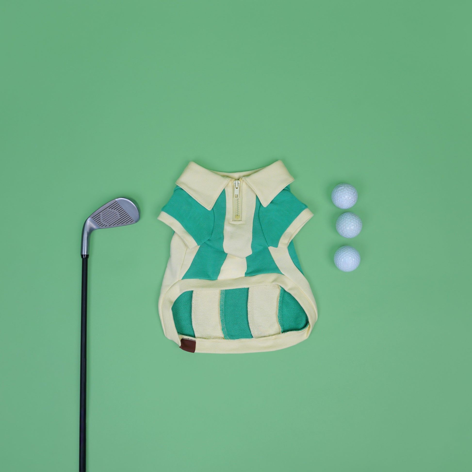 Green and beige striped dog sweater with golf club and balls on a green background