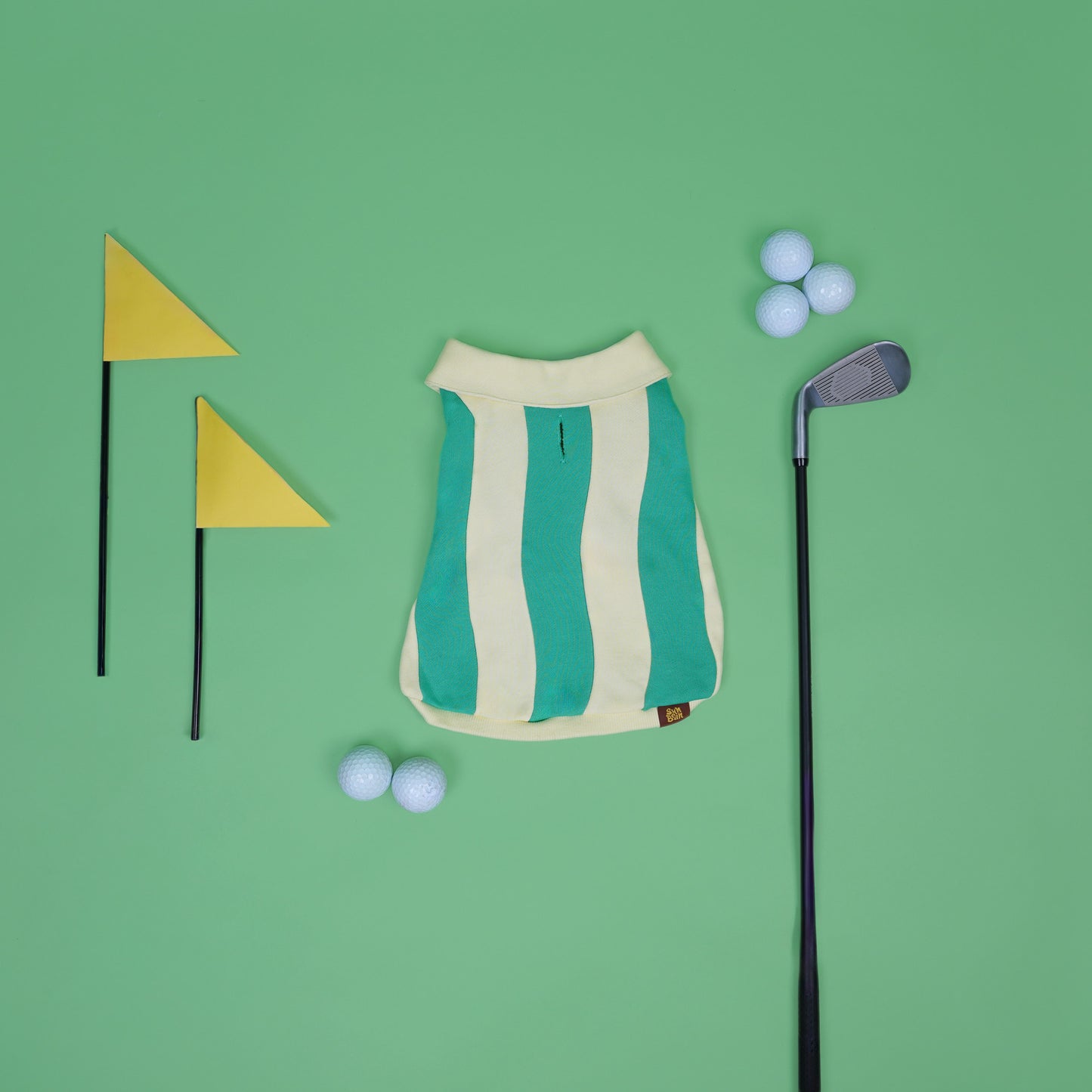 Dog costume with green and white stripes, golf club, golf balls, and flags on a green background