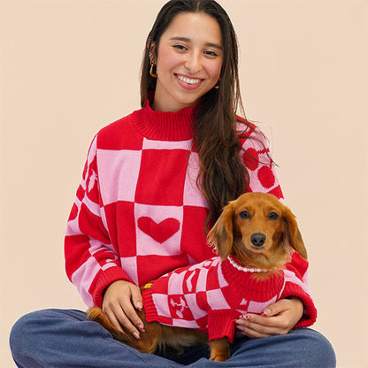 Woman wearing a red and white checkered sweater holding a dog also in a matching sweater against a beige background |SUNBEAN